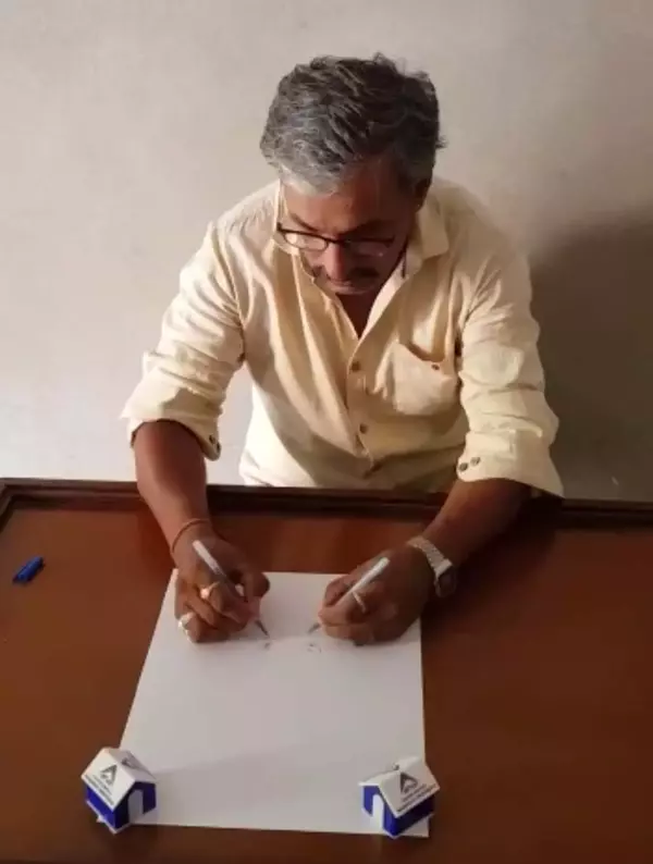 Heeralal Chitrakar Bhadrecha is making a painting on plain white paper using both hands simultaneously