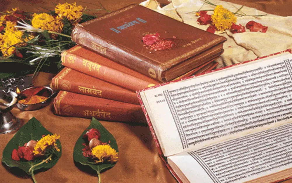 Four Vedas books and some yellow flowers and green leaves