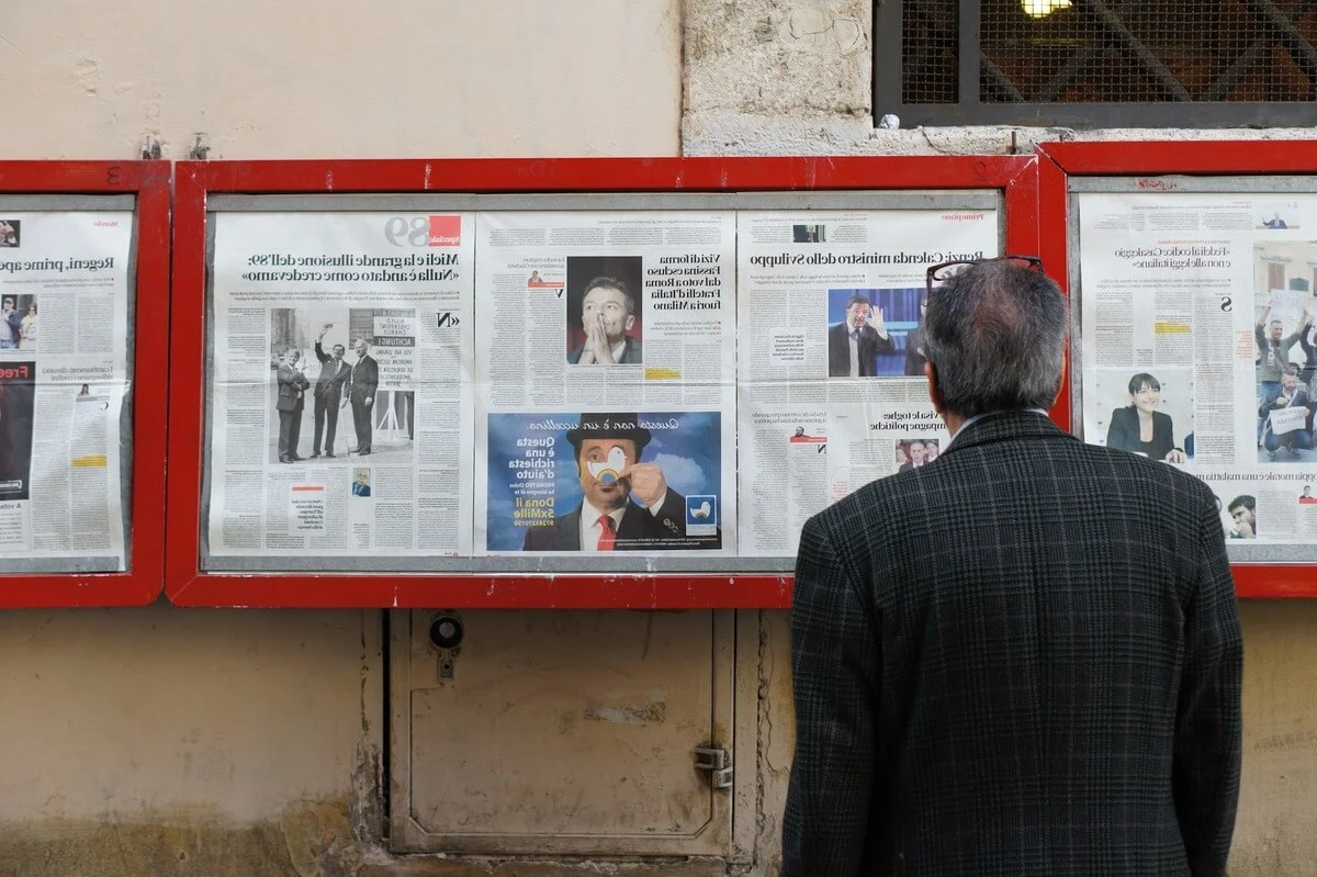 An old man reading newspapers pinned on wall for knowing latest news and updates